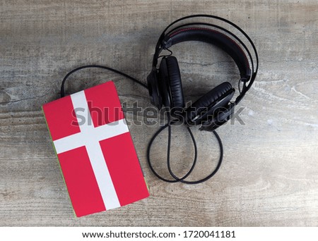 Headphones and book. The book has a cover in the form of Denmark flag. Concept audiobooks. Learning languages.