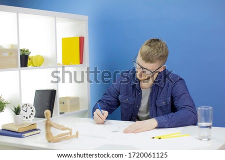 Young creative fashion designer working on sketches, draws pencil sketches in blue workspace, dummy on desk. Concept of art, inspiration, talent, freelance, fashion, design, mode, style