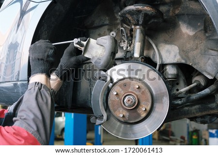 Car maintenance in the service center, a close-up of the replacement of the front brake pads, compression of the brake caliper.