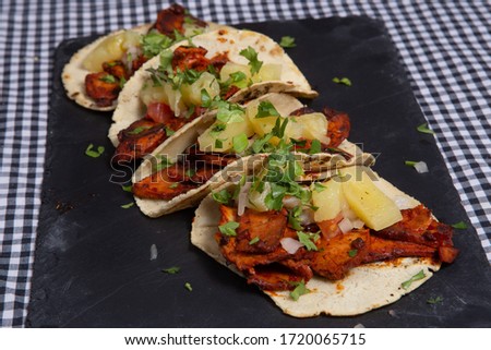 Mexican tacos with chicken meat, avocado, tomato, cucumber and red onion. Table, cuisine.