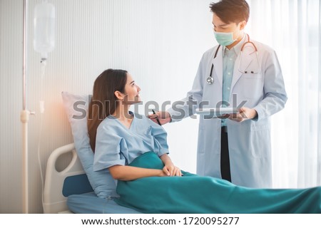 Medicine and health care concept.  Asian doctor is taking care patient woman in hospital.doctor or nurse wear protection mask checking and takecare infection people from covid-19 .