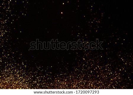 Abstract holiday background, gold Stardust on black. Sequins in focus and out of focus.