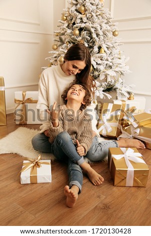 fashion photo of beautiful family celebrating Christmas with decorated tree and presents