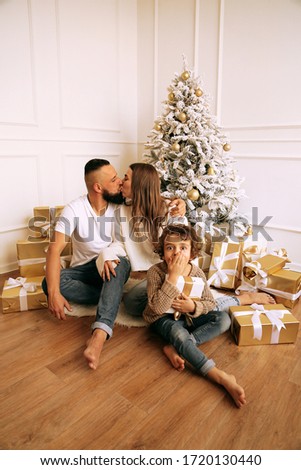 fashion photo of beautiful family celebrating Christmas with decorated tree and presents