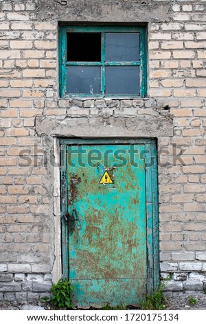 old metallic green door with licked paint and "attention, high voltage" sign below the broken window surrounded by bricks flat background for web site, industrial mood, abandoned rusty texture grunge