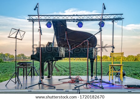 Chamber music in nature. A stage with a piano set in a agriculture field 