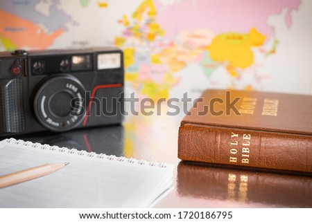 Holy Bible, notebook, and camera with the background of world map or Asia map.