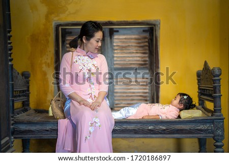 Mother and daughter with Vietnam culture traditional dress sitting at ancient town Hoi an.