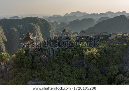 Aerial image of tourists flocking to see a giant dragon statue on top of a hill next to Ninh Binh, Vietnam