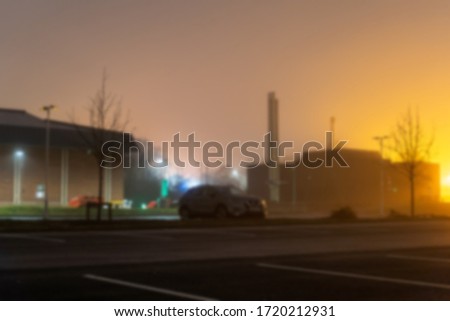 A car park on an empty industrial estate on a misty winters night. With a blurred, out of focus edit