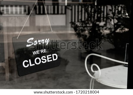 Sorry we're closed sign hanging on a dirty glass door.
