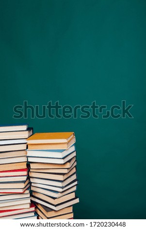 many stacks of educational books for exams at the university in the library on a green background