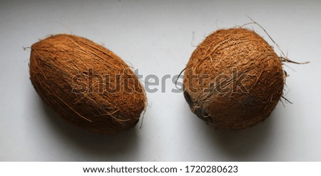 Two coconuts, one round second oval lie nearby. Photo taken with daylight.
The picture was taken with selective focus.
