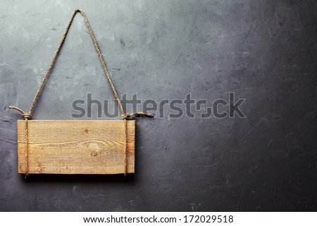 Wooden signboard hanging on rope on gray textured wall with copy space