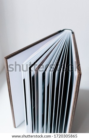 An open photo book with a wooden cover stands on the white background. Flat lay.