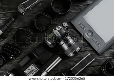 Flat lay composition with equipment for professional photographer on black wooden table