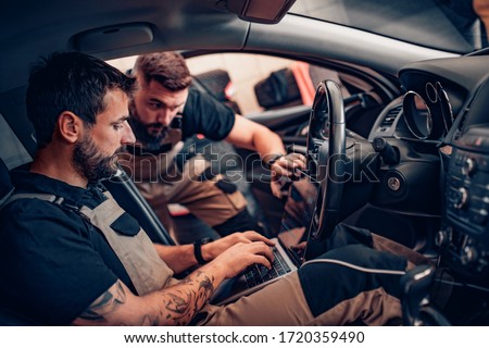 Two modern mechanics doing diagnostic in the car. Concept of work. Royalty-Free Stock Photo #1720359490