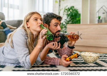 Happy couple laying on floor and playing video games.Young couple playing video games in their apartment.Hobbies and leisure concept.