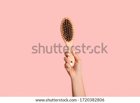 Close up of millennial girl holding wooden hairbrush on pink background Royalty-Free Stock Photo #1720382806