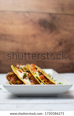 Mexican Taco with ground chicken side view with on white dish on white distressed table with wood color background