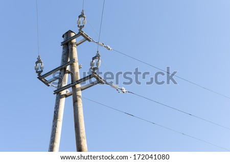 Power lines on wooden pillar with blue sky in background.