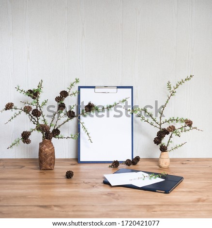 Interior Design Desktop. Clipboard with Blank A4 Paper Mock up and Larch Branches with Cones, Computer Tablet. Stylish Minimal Home Decor