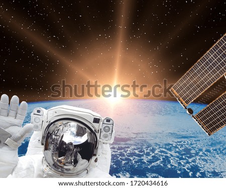 Astronaut waves against beautiful sunrise. The elements of this image furnished by NASA.
