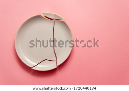 broken white plate on pink background, concept visual Royalty-Free Stock Photo #1720448194