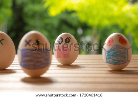 Eggs with drawings of faces with chinstraps. Concept of protection and social distancing. Eggs on a table. Contagious disease concept.
