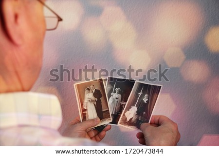 old man’s male hands hold old retro family photos in sepia color and looks at photographs of his and his sisters, made in 1963 - 1964, genealogy concept, ancestral memory, family  Royalty-Free Stock Photo #1720473844