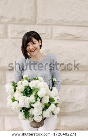 Woman holding a bouquet of seasonal flowers. Florist with big bunch of various white flowers.