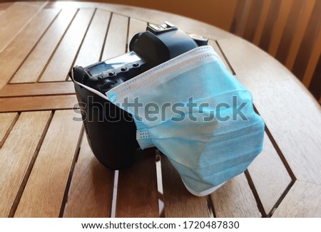Surgical protective mask on reflex camera. Metaphor about the negative effect of the pandemic, caused by the coronavirus covid-19, on the photographic sector.