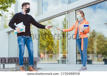 Two students during coronavirus crises with mobile phones and contract tracing app Royalty-Free Stock Photo #1720488958