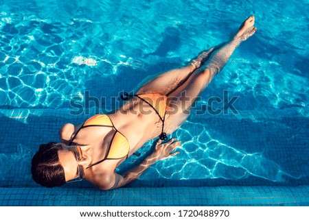 Beautiful woman relaxing in swimming pool of resort or hotel enjoying the water