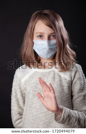 Girl with safety mask from coronavirus showing stop sign. Isolated on black background