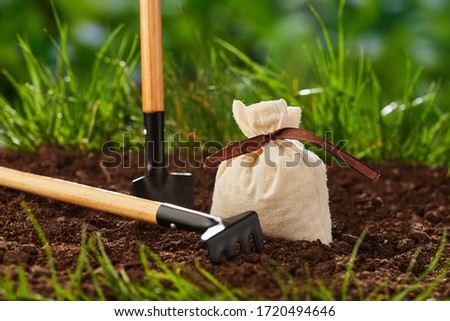 Small gardening tools: shovel, rake for plants and bag for grain lie on the ground. Agriculturual concept