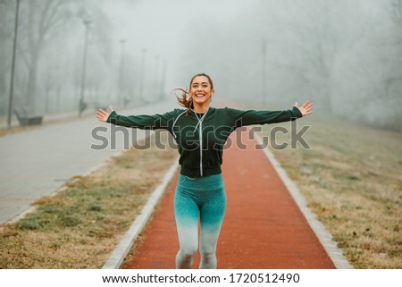 Close photo of young runner breathing fresh air outstretching arms on foggy morning.