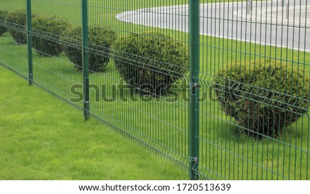 neat metal fence and bushes of a park zone in the city Royalty-Free Stock Photo #1720513639
