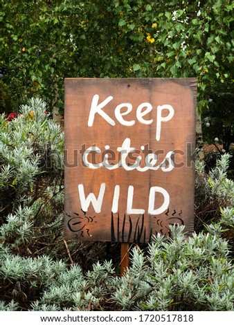 Hand painted timber sign ‘Keep Cities Wild’ surrounded by plants and greenery, Earth Day
