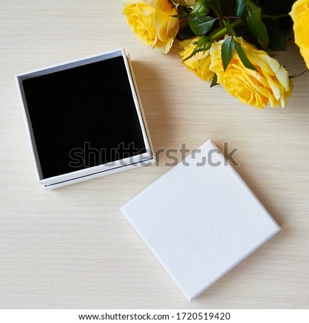 Top view for presentation. Empty box for jewelry, gift. Place for logo, sale text. Yellow roses bouquet on the table. Royalty-Free Stock Photo #1720519420