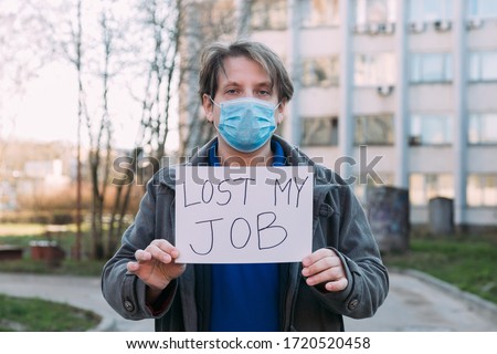 Job loss due to COVID-19 virus pandemic concept. man holds sign lost my job. Male sitting on stairs of building, former place of work in business center Royalty-Free Stock Photo #1720520458