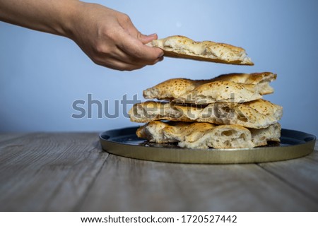 Ramadan concept about solidarity, close-up of the woman puts 4 pieces of pita in a row on the plate.