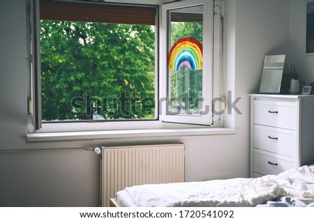 Open window in room with green trees on background. Painting rainbow on window. Rainbow painted with paints on glass is a symbol for many meanings. Feeling of freshness, spring, fresh air, revive.