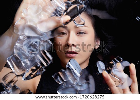 Beautiful woman portrait with dark hair. woman under the ice. woman touching the mirror. black background. 