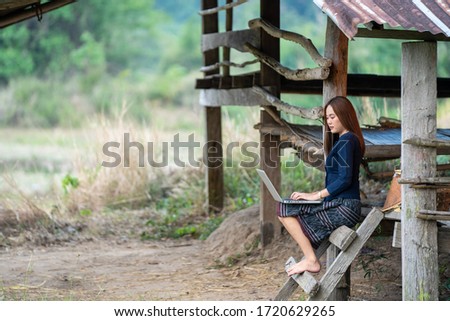 Beautiful women in rural Thailand are using laptop in the rice field.