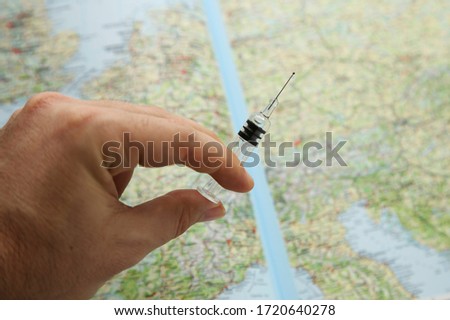 A hand holding a medical syringe that contains a vaccine. Travel medication concept image.