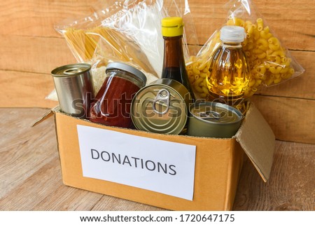 Donations box with canned food on wooden table background / pasta canned goods and dry food non perishable with cooking oil rice noodles spaghetti macaroni donations food concept Royalty-Free Stock Photo #1720647175