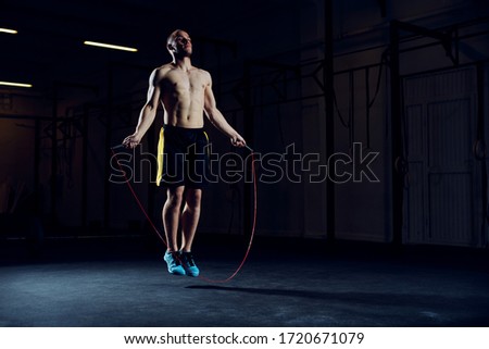 Athletic young man training with skipping rope. Cardio workout with minimal equipment Royalty-Free Stock Photo #1720671079