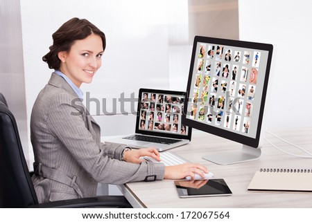 Portrait Of Happy Young Businesswoman Browsing Pictures On Computer