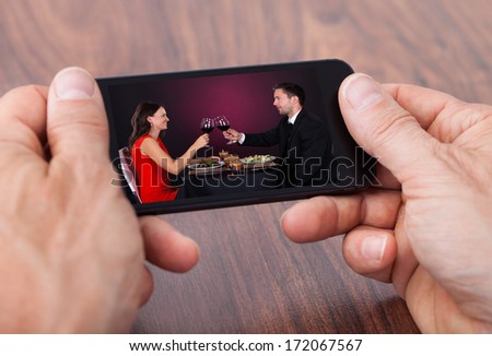 Close-up Of A Person's Hand Watching Video On Cellphone